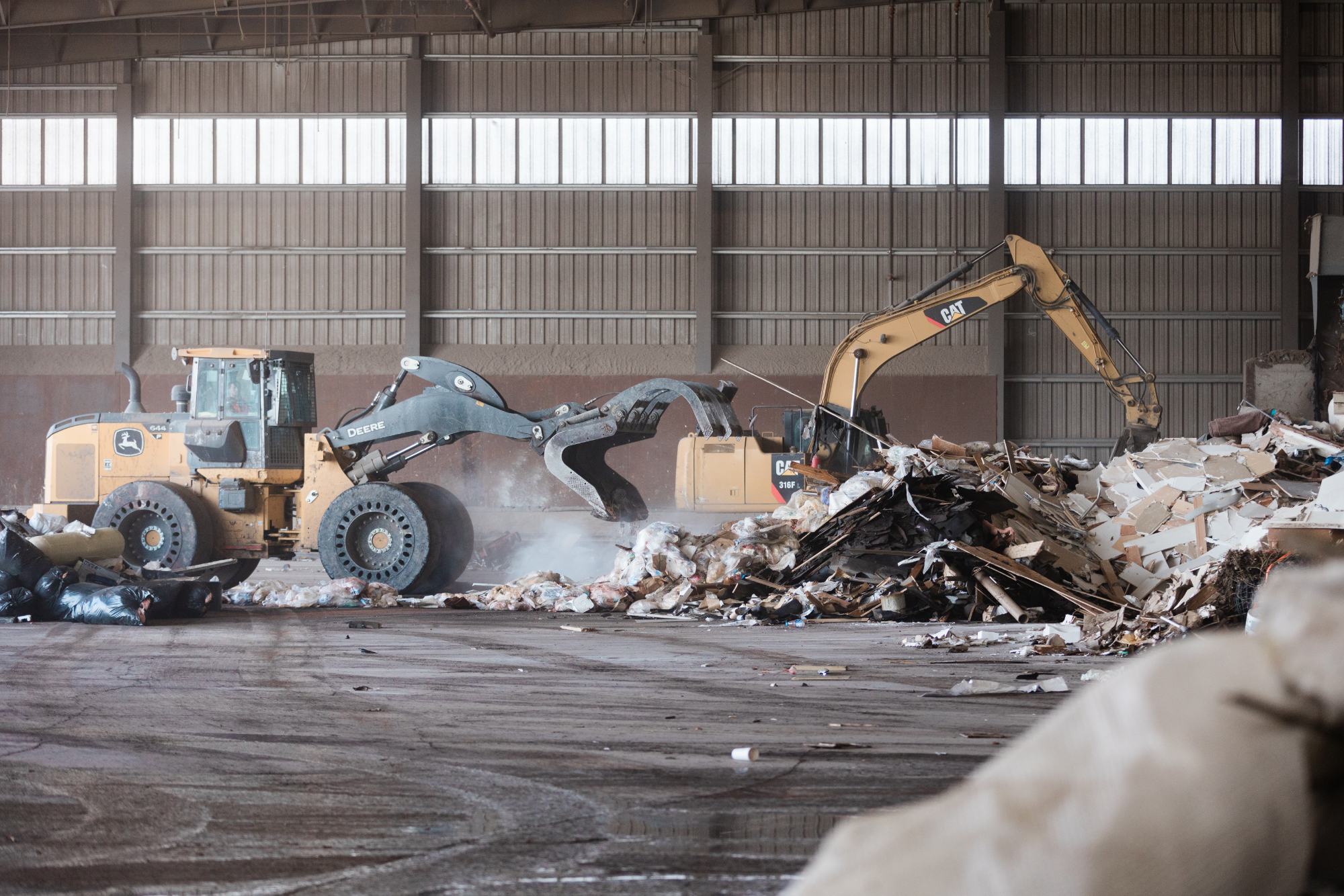 trucks moving piles of construction waste in sorting facility